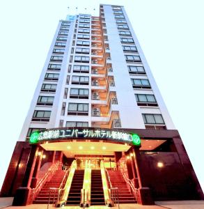 广岛Hiroshima Ekimae Universal Hotel的前面有楼梯的高大的白色建筑