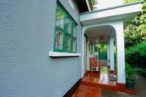 莫希Janibichi Adventures hostel的拥有绿色窗户的房子的入口