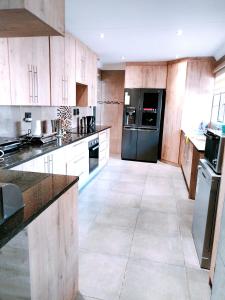 塞昆达Reutlwane Gardens house的厨房配有木制橱柜和黑色冰箱。