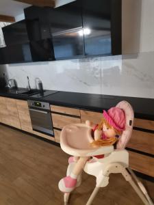 JasenicaChatka Katka的坐在厨房高脚椅上的娃娃