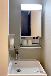 泉佐野My Home Inn Izumisano的一间带水槽和镜子的浴室