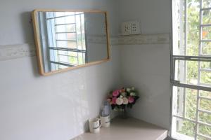 芹苴79/10 Tran Phu House的浴室里装有镜子,花瓶