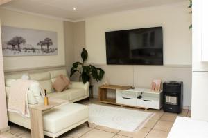 阿尔伯顿Neapolitan Guesthouse的客厅配有白色沙发和平面电视。