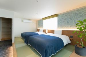 仓敷Nagi Kurashiki Hotel&Lounge的一间种植了盆栽的房间里,有两张床