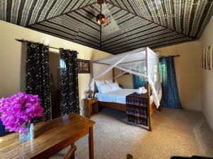 MbodièneMariama Lodge的一间卧室配有一张天蓬床和一张桌子