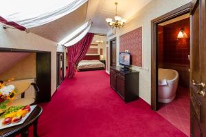 伊万诺-弗兰科夫斯克Franz Hotel&Restaurant的酒店客房的粉红色地毯走廊设有一张床和电视。