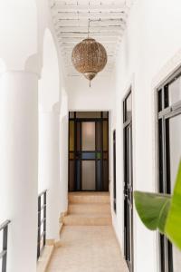 马拉喀什Riad La Lumière d'Étoile的走廊设有白色墙壁和带吊灯的天花板
