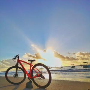 圣米格尔-杜斯米拉格里斯Angá Beach Hotel的一辆红色自行车停在海滩上,日落时分