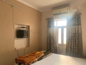 比卡内尔MOON HAVELI的一间卧室设有一张床、一台电视和一个窗口。