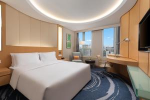 深圳Crowne Plaza Shenzhen Futian, Near by Futian Station and Coco Park, Outdoor Heated Pool的卧室配有一张白色大床和一张书桌