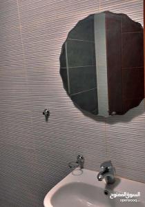 Umm Uthainahشقه في عبدون للإيجار的浴室水槽和墙上的圆镜子