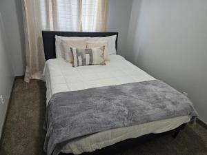 萨斯卡通3 bedroom Town in Stonebridge unit 303的一张带枕头和灰色毯子的大床