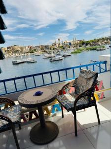 阿斯旺La Terrace的阳台配有桌椅,享有海港的景致。