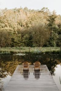 普莱贝-克里斯特Gîtes du Bulz, en pleine forêt proche de la mer的两把椅子坐在湖边的码头上