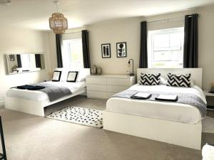 埃尔森汉姆Stansted Coach House的白色卧室设有两张床,配有镜子