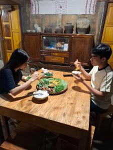 Nà GiảoNhất Nhất Homestay的一群坐在木桌旁吃食物的人