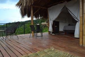 金巴亚Encanto Toscano的木制甲板上的帐篷,配有一张床和椅子