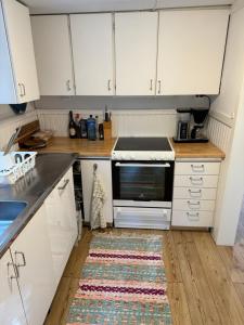 厄勒布鲁Mysig stuga i Nävesta的厨房配有白色橱柜和地板上的地毯