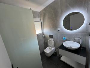 萨兰达Garden Villa Apartments的一间带卫生间、水槽和镜子的浴室