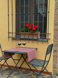 圣吉米纳诺农庄卡萨酒店的一张桌子、两把椅子和一个鲜花窗口