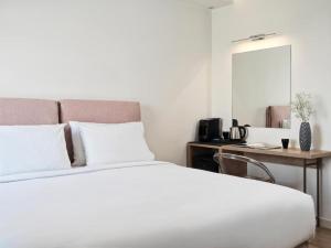 马蒂NLH Mati Seafront - Neighborhood Lifestyle Hotels的卧室配有一张白色的床、一张桌子和一面镜子