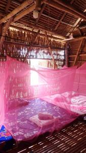 OBT -The Corn Bungalow的大型客房配有粉红色的床和蚊帐。