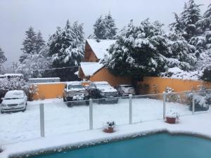 圣卡洛斯-德巴里洛切HOTEL LE CHARME con parking的积雪覆盖的院子,有停放的汽车和房子