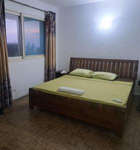贝拉Yulendo Backpackers的一间卧室配有一张带绿色床单的床和窗户。