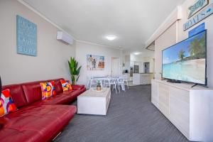 马库拉Absolute Beachfront Penthouse - Ramada Marcoola的客厅配有红色沙发和平面电视