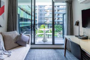 墨尔本Corporate Living Accommodation Abbotsford的酒店客房设有沙发、书桌和窗户。
