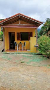卡西米鲁-迪阿布雷乌Pousada Casa da montanha的一个小黄色房子,配有桌子和椅子