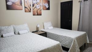 圣佩德罗苏拉Casa Altamira的一间卧室设有两张床和一扇黑色的门