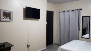 圣佩德罗苏拉Casa Altamira的一间卧室配有一张床,墙上设有一台平面电视