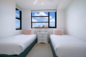 布里斯班Regatta Hideaway - A Breezy Balcony Residence的带2扇窗户的客房内的2张床