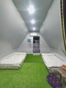 An Vĩnh PhướngHomestay Hang Câu的一间设有两张床的客房,铺有绿色地毯