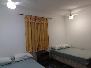 阿拉鲁阿马Casa Area Gourmet的一间卧室设有两张床和一个带窗帘的窗户。