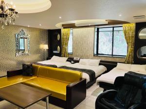 御殿场市Hotel Square FujiGotemba的酒店客房带两张床和一张黄色沙发