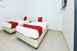 珍南海滩OYO 275 Senyum Inn的客房内的两张床,配有红色和白色床单
