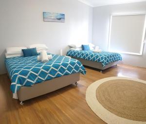 文森提亚Vincentia Breeze by Experience Jervis Bay的一间卧室配有两张带蓝白色床单的床