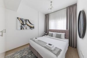迪拜Comfortable 2bd Apartment Next To Metro & Mall的白色的卧室设有一张大床和一个窗户