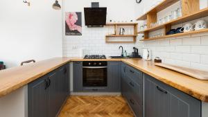 克拉科夫Apartamenty Sun & Snow Basztowa的厨房配有灰色的橱柜和木制台面