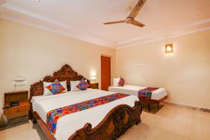 海得拉巴FabHotel Maruthi Residency的一间卧室配有两张床和吊扇