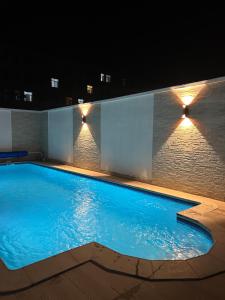 塔那那利佛ZARA HOTEL的夜间游泳池,墙上有灯