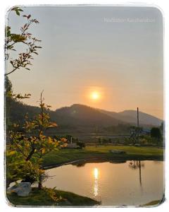 北碧Nex Station Kanchanaburi的日落在湖上,太阳落山