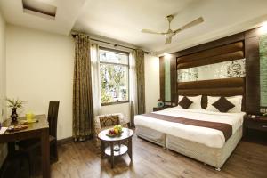 新德里Hotel Good Times Near Metro的配有一张床、一张书桌和一扇窗户的酒店客房