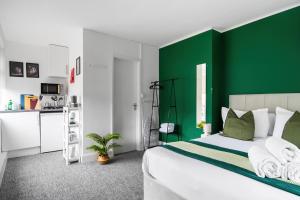 East BarnetLivestay Affordable En-Suite Studio Rooms in London, N14的一间绿色和白色的卧室,配有一张床和一个厨房