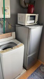 东京Ueno Iriya hostel的厨房里洗衣机上面的微波炉