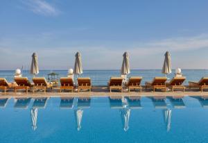玛利亚Alexander Beach Hotel & Village Resort的毗邻大海的带椅子和遮阳伞的游泳池