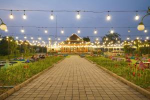 PasirkudaPelangi Park Hotel & Resort的一座带灯光的花园以及一座建筑的背景
