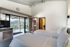 PasirkudaPelangi Park Hotel & Resort的一间带两张床、一台电视和一个阳台的卧室